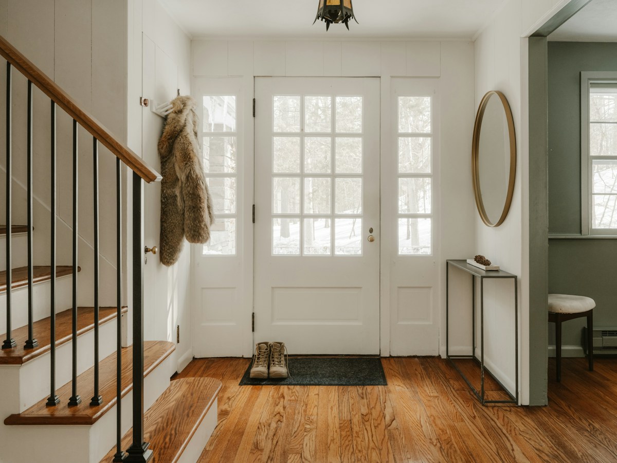 A cozy entryway with wooden stairs and a glass door